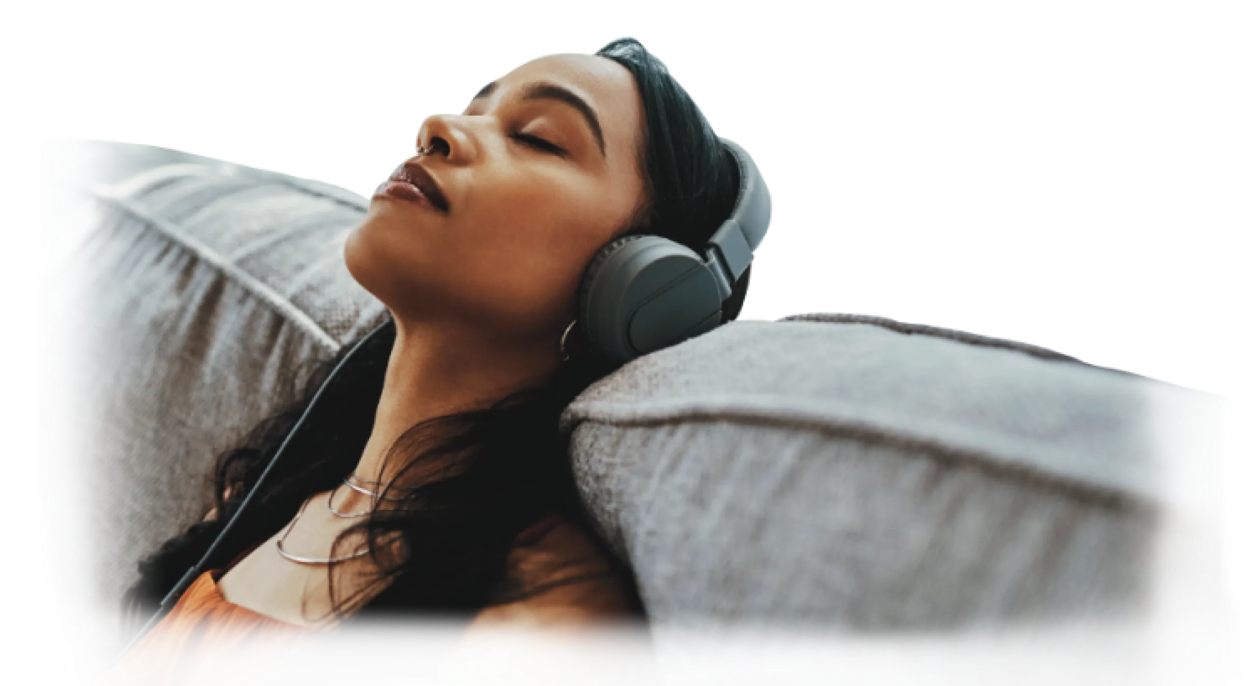 A person relaxing on a couch listening to music on headphones